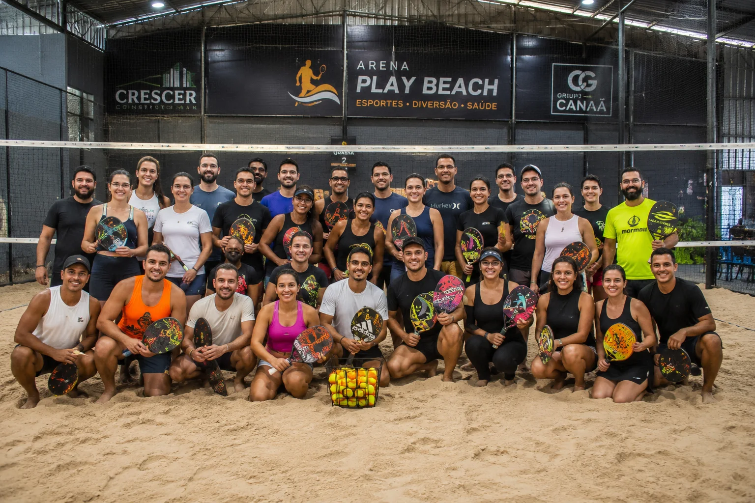 Grupo reunido com raquetes em uma arena de Beach Tennis